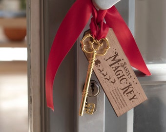 May include: A gold-colored key with an ornate design hangs from a door handle with a red ribbon. A wooden tag with the text "Santa's Magic Key" is attached. The key is designed to be left out for Santa.