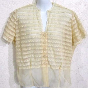 May include: A white lace blouse with a button-up front and short sleeves. The blouse has a delicate, feminine design.