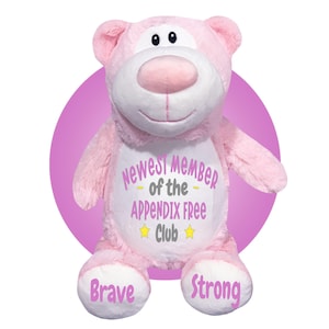 May include: A pink plush bear with a white face and belly, and a pink circle behind it. The bear has the text "Newest Member of the Appendix Free Club" on its belly, with the words "Brave" and "Strong" on its feet.