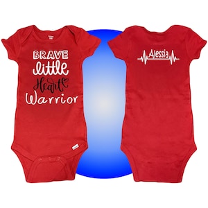 May include: Two red short-sleeved shirts. One shirt says "Brave little heart warrior" in black and white lettering. The other shirt has a white heartbeat graphic with the name "Alessia" in white lettering.