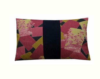 May include: A rectangular throw pillow featuring a central vertical dark navy blue band. The side panels display a pattern of overlapping pink and gold rectangles interspersed with light yellow sections decorated with pink cherry blossom clusters.