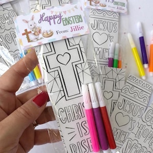May include: Easter colouring bookmarks with markers. Each bookmark features a cross or religious message, with the words "Happy Easter" and "From: Jillie" on the attached tag. The markers are in various colours.