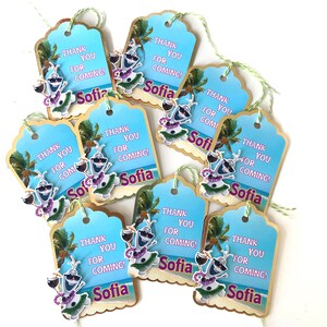 May include: A collection of gift tags with a tropical theme. Each tag features a blue sky background, a cartoon character, and the text "THANK YOU FOR COMING!" and the name "Sofia". The tags are adorned with green string.