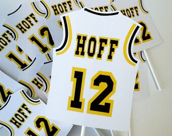 May include: White and yellow basketball jersey cupcake toppers with the name "HOFF" and the number "12" printed on them.