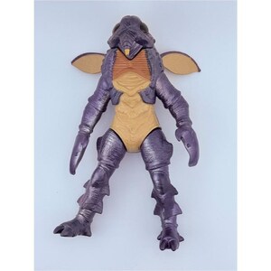 May include: A purple and tan insectoid action figure with a textured exoskeleton, large dark eyes, small wing-like appendages on the shoulders, and clawed hands. The figure features a segmented body design with a tan chest and abdomen area.