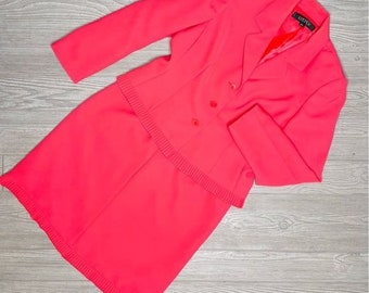 May include: A bright pink skirt suit with a double-breasted blazer and a skirt with a ruffled hem. The blazer has a label that reads "Just B".
