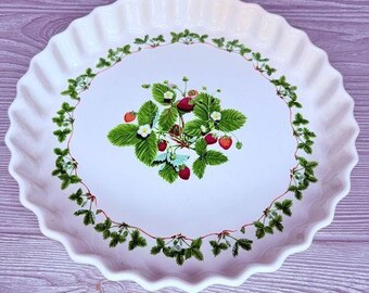 May include: White ceramic pie dish with a scalloped edge and a green and red strawberry design.