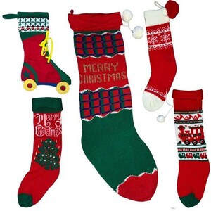 May include: Five Christmas stockings with different designs. One stocking is red with a green and white plaid pattern and the words "Merry Christmas" in gold. Another stocking is red with a white and green Christmas tree design. A third stocking is red with a white and blue snowflake design. A fourth stocking is red with a white and green train design. The fifth stocking is red with a white and blue roller skate design.