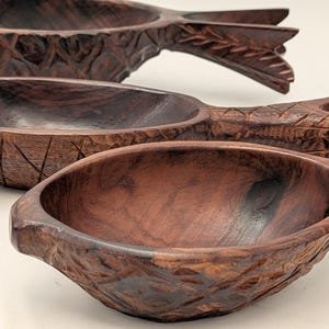 May include: Three hand-carved wooden bowls in a pineapple shape. The bowls are made of dark brown wood with intricate carved details. The bowls are arranged in a diagonal line, with the closest bowl in focus.