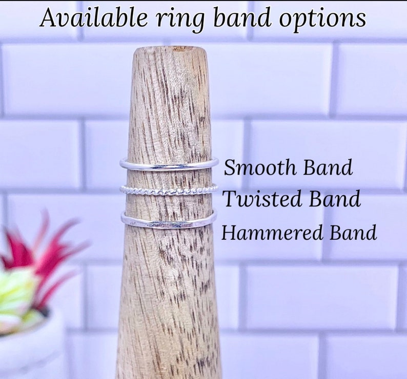 K&ouml;nnte beinhalten: Drei silberne Ringe auf einem Holzst&auml;nder. Die Ringe sind mit "Smooth Band", "Twisted Band" und "Hammered Band" beschriftet.