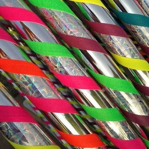 Può includere: Primo piano di più cerchi argentati con nastro colorato avvolto attorno. Il nastro è di vari colori, tra cui rosso, verde, giallo e viola. I cerchi sono lucidi e riflettenti.