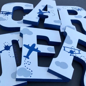 May include: Blue and white wooden letters spelling out the name "CARTER" with a blue airplane and cloud design.