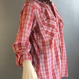 May include: A red and white plaid long-sleeved shirt with a button-down collar and two chest pockets.