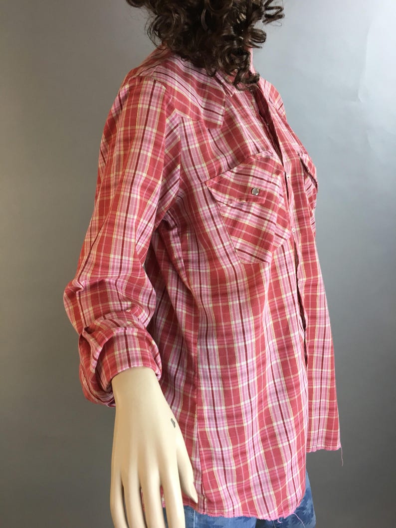 May include: A red and white plaid long-sleeved shirt with a button-down collar and two chest pockets.