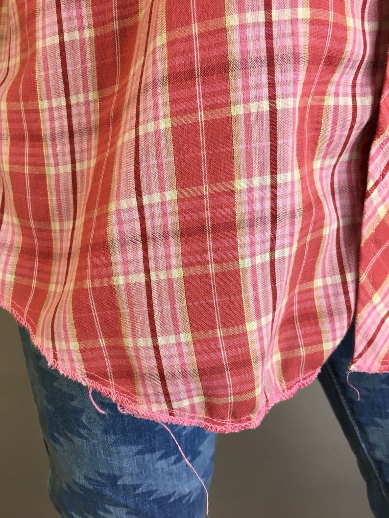May include: A red and white plaid shirt with a pink seam. The shirt is frayed at the bottom edge.