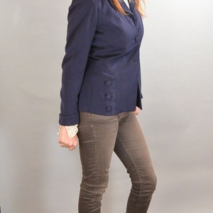 May include: A woman wearing a navy blue blazer with brown jeans and brown wedge heels.