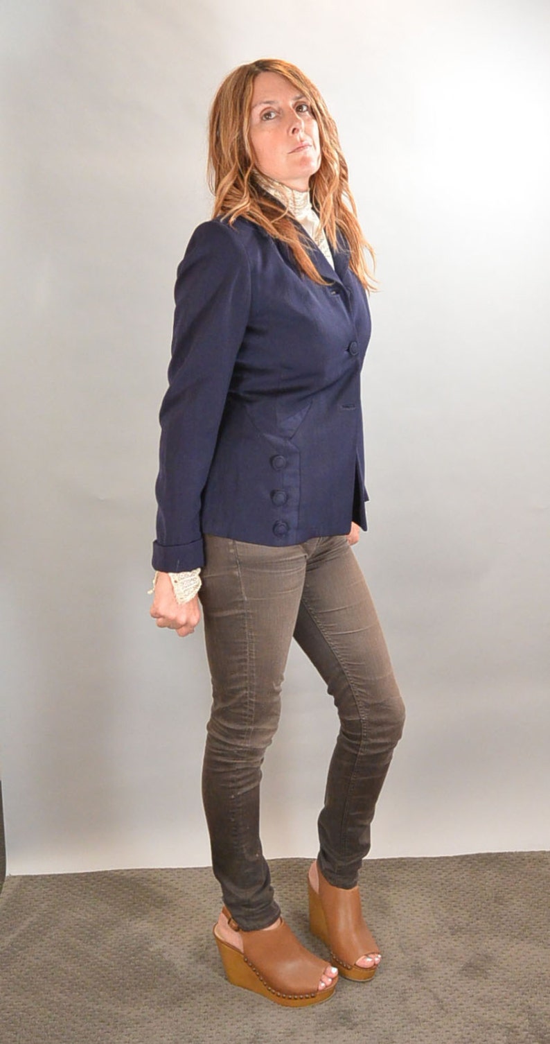 May include: A woman wearing a navy blue blazer with brown jeans and brown wedge heels.