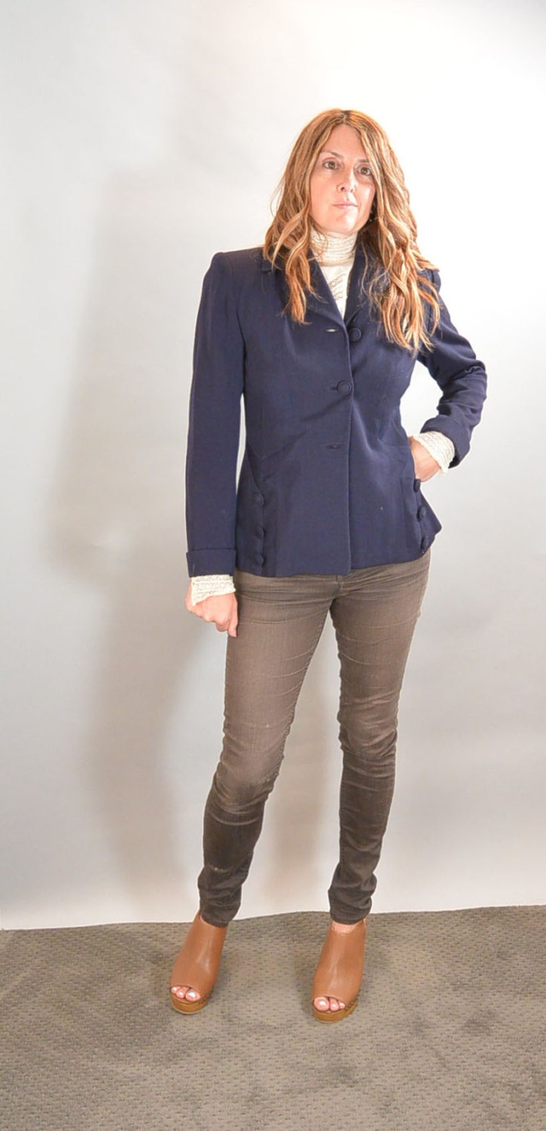 May include: A woman wearing a navy blue blazer with brown pants and brown open-toe heeled shoes.