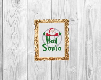 May include: A framed cross-stitch design with a red and white Santa Claus figure inside a pentagram with the text "Hail Santa" in green.