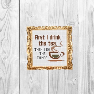 Puede incluir: Una imagen enmarcada en dorado con el texto "First I drink the tea. Then I do the things" y una imagen de dibujos animados de una taza de té humeante.