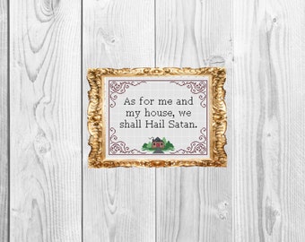 May include: A framed cross-stitch with a gold frame and a white background. The cross-stitch features the text "As for me and my house, we shall Hail Satan." with a small red house and green trees below the text.