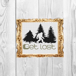 May include: A framed cross-stitch design featuring a black silhouette of Bigfoot walking through a forest with three pine trees. The text "Get lost" is written below the image in green.
