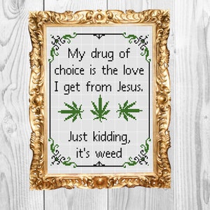 Puede incluir: Un diseño de punto de cruz enmarcado con un dicho humorístico sobre la hierba. El texto dice: "Mi droga de elección es el amor que recibo de Jesús. Es broma, es hierba."