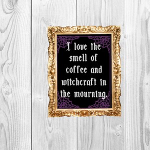 May include: A framed print with a black background and purple spiderwebs. The text reads "I love the smell of coffee and witchcraft in the morning."