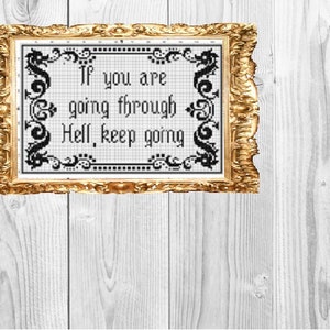 May include: A framed cross-stitch with a black and white design. The text reads "If you are going through Hell, keep going."