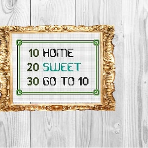 May include: A framed cross-stitch design with green and blue thread. The design reads "10 HOME 20 SWEET 30 GO TO 10".