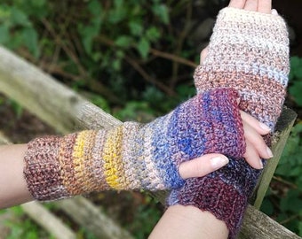 May include: A pair of colorful crocheted fingerless gloves with a gradient of brown, yellow, blue, and purple. The gloves are made with a textured stitch.