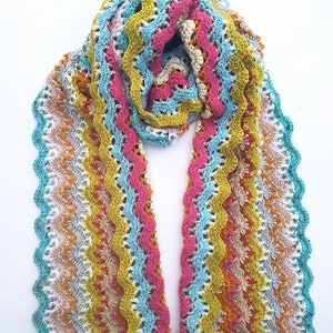 May include: A colourful crocheted scarf with a wavy pattern in shades of pink, blue, yellow, and white.