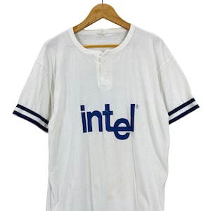 May include: White short-sleeved t-shirt with a blue "intel" logo and blue and white striped sleeves.