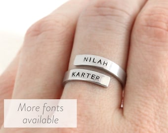 Puede incluir: Un anillo de plata con dos bandas, una grabada con el nombre "Nilah" y la otra con el nombre "Karter".