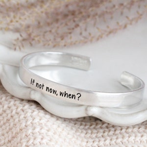 May include: Silver bracelet with the inscription "If not now, when?"
