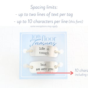 Puede incluir: Dos etiquetas met&aacute;licas con las frases "life is tough" y "but so are you" en texto negro. Las etiquetas est&aacute;n unidas a una tarjeta azul claro con el texto "10th Floor Treasures". La imagen tambi&eacute;n incluye l&iacute;mites de espaciado.