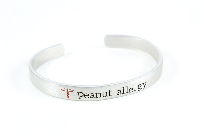 May include: Silver bracelet with the text "Peanut allergy" and a red medical symbol.