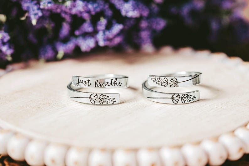 May include: Two silver rings with a delicate floral design and the words "Just Breathe" engraved on one of the rings.