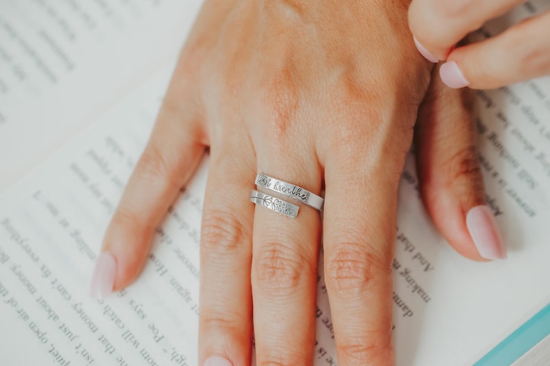 May include: A silver ring with the words "Inhale, exhale" engraved on it. The ring is worn on a person's finger.
