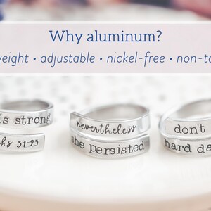 May include: Three silver-colored wrap rings with inspirational quotes. The rings are stamped with phrases like "she is strong" and "nevertheless she persisted." The image also includes text that says "Why aluminum?" and lists the benefits.