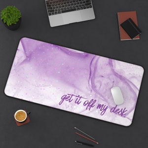 May include: Purple and white desk mat with a marble pattern and a scattering of stars. The text "get it off my desk" is written in purple on the mat.