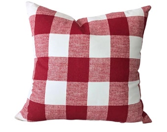 May include: Square decorative pillow with a red and white buffalo check pattern. The pillow has a soft, textured appearance and is designed for home decor. The classic plaid design adds a touch of rustic charm to any room.
