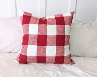 May include: Red and white buffalo check pillow cover. The pillow cover is made of a soft, textured fabric and has a square shape.