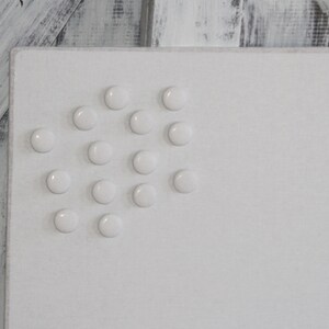 May include: White magnetic board with white round magnets arranged in a loose pattern.