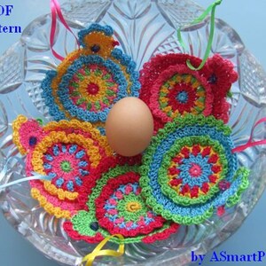 May include: Five colorful crocheted Easter egg ornaments in a glass bowl with a white egg in the center. The ornaments are decorated with a variety of colors, including red, yellow, blue, green, and pink. The ornaments are attached to pink and green ribbons.