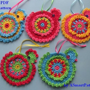 May include: Five crocheted ornaments shaped like chickens with colourful circular patterns in shades of pink, yellow, green, and blue. Each ornament has a loop for hanging.