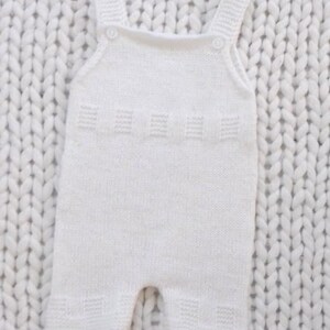 May include: White knitted baby romper with straps. The romper has a simple design and is made of a soft, comfortable material.