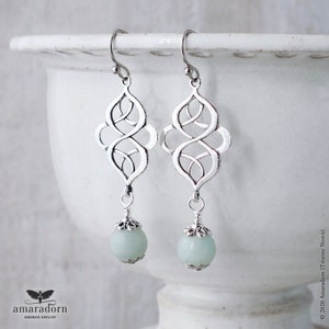 An elegant pair of earrings featuring antiqued silver plated celtic knots combined with dangling pale mint green amazonite gemstone beads finished with pretty silver bead caps and a wire wrapped finish. Attached to your choice of silver ear wires.