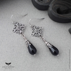 May include: Silver filigree dangle earrings with black teardrop-shaped beads.