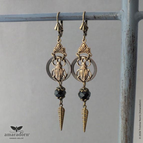Handcrafted beetle earrings fusing Victorian naturalist aesthetics with Egyptian Revival drama — genuinely wearable cabinet-of-curiosities art.